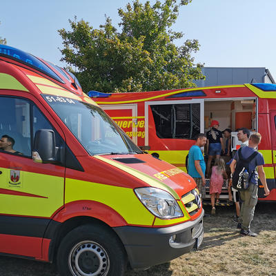 Bild vergrößern: Besucher schauen sich zwei Rettungsfahrzeuge an