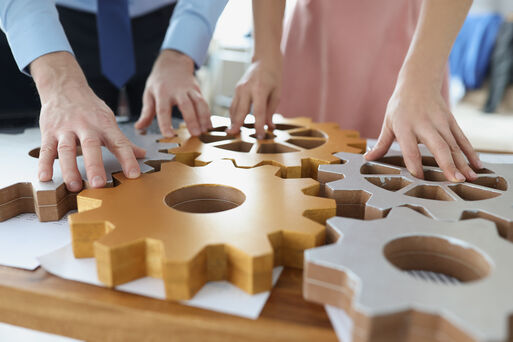 Businesspeople put wooden gears on workplace together, work in team